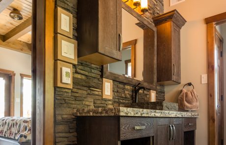 Dark wood bathroom vanity on a stone wall.