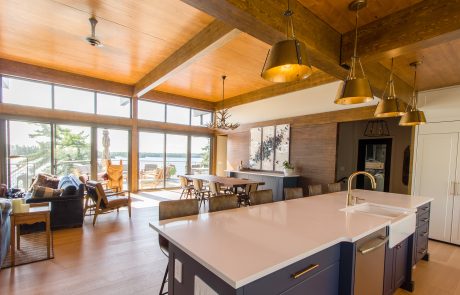 Kitchen island with dark blue cabinets and white countertop. View of dining/living area overlooking the lake.