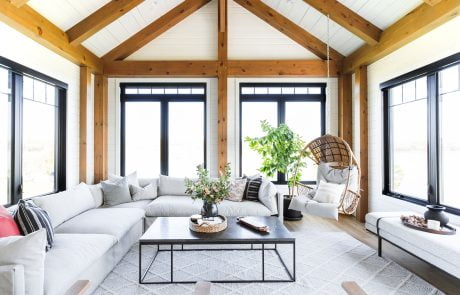 Family room with wood accent beams and large windows trimmed with black.