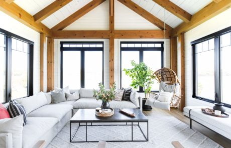 Family room with wood accent beams and large windows trimmed with black.