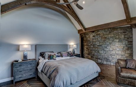 Bedroom with stone accent wall and herringbone patterned flooring.