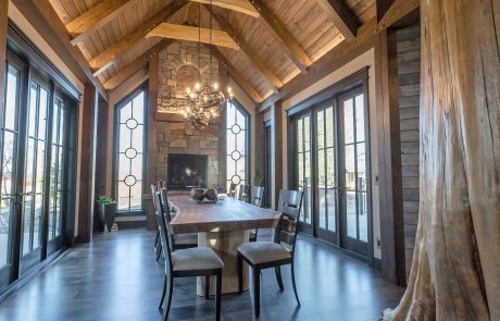 Dining room with windows all around and a fireplace in the center.