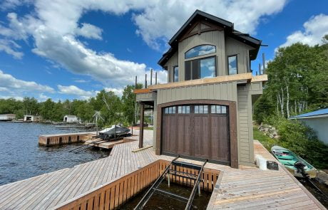Green boathouse with dark wood accents and garage door.