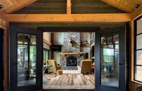 View of entrance through black french doors into the living room, with the stone fireplace being the central focus.