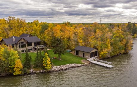 Home exterior with Fall trees. Boathouse and docks in the lake