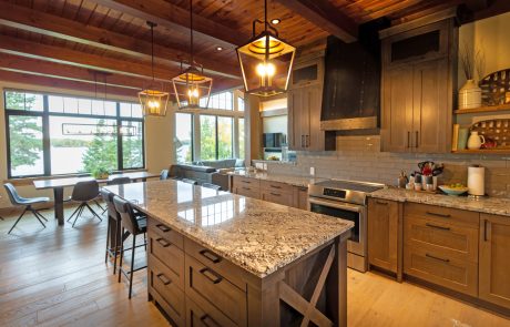 Kitchen and dining area with light wood floor, medium wood cabinets and marbled stone countertops